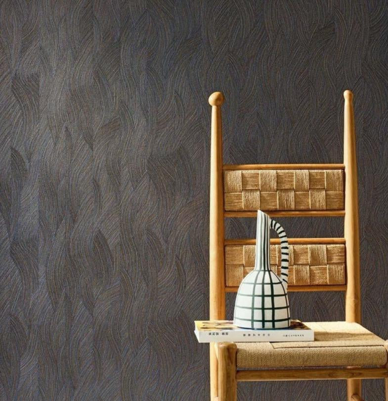 A styled interior scene showing a wooden chair with a woven seat against a dark textured wallpaper, alongside a color card panel labeled 'Jassue' and product details for wallpaper. Because a real environment/staged room setting is present, this fits Lifestyle rather than Product/Packaging.