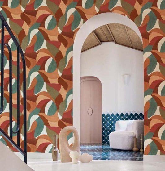 A wallpaper product presentation showing a patterned wall in a styled interior on the left and a dark product panel on the right labeled 'Mandela' with swatches and dimensions. The wallpaper pattern features overlapping abstract leaf-like shapes in rust, beige, teal, and brown tones.