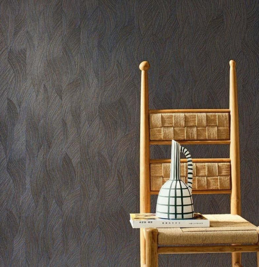 A styled interior scene showing a wooden chair with a woven seat against a dark textured wallpaper, alongside a color card panel labeled 'Jassue' and product details for wallpaper. Because a real environment/staged room setting is present, this fits Lifestyle rather than Product/Packaging.